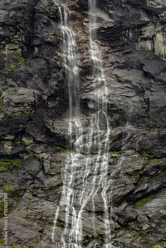 A close-up shot of a waterfall, where the cascading water crashes against the rugged rocks below. The sheer power of the water is evident as it splashes and churns, creating a dynamic scene