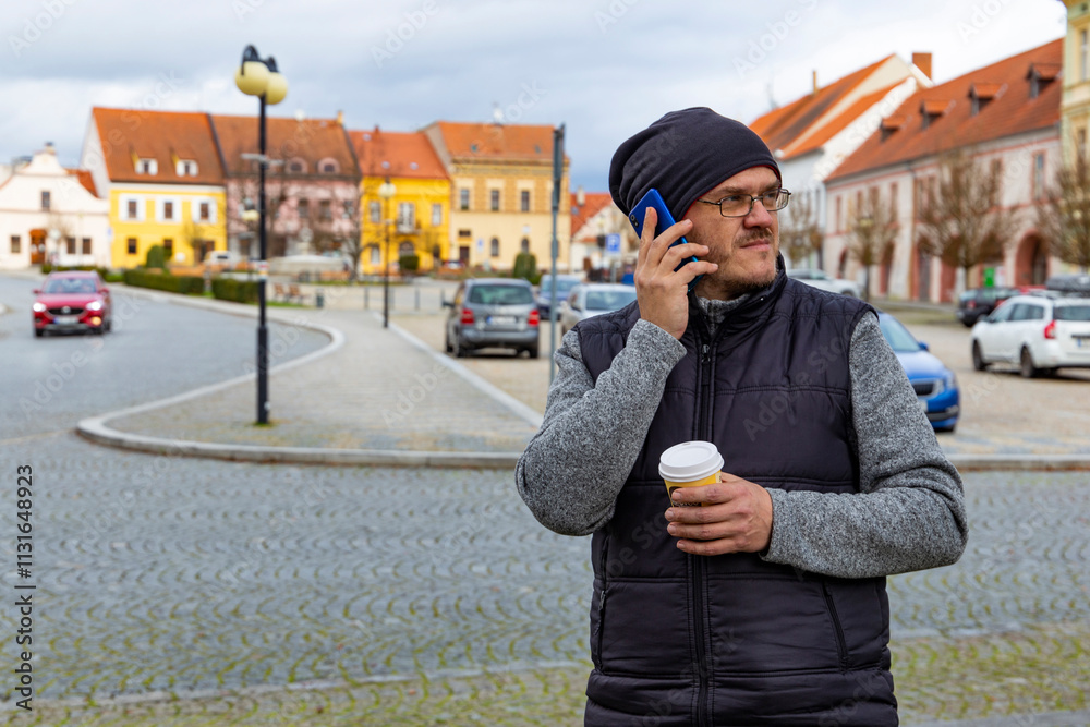 A man with a cup of coffee walking through an autumn city.