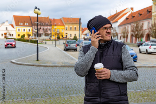 Obraz na płótnie A man with a cup of coffee walking through an autumn city. w salonie