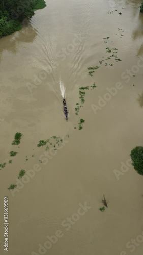 Aerial view of a wooden boat cruising on a murky river