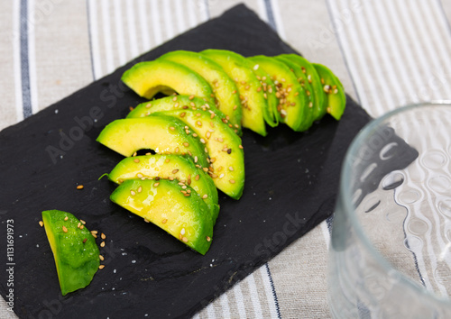 Beautifully sliced avocado with sesame seeds on a plate, serve avocado on a festive table. High quality photo