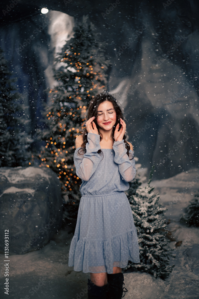 Fototapeta premium Woman smiles in a winter forest with snowfall. Evergreen trees and holiday lights, festive atmosphere for Christmas and New Year celebrations.