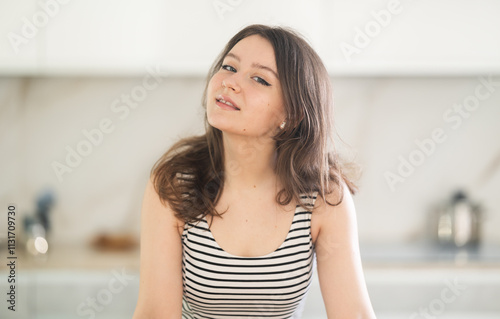 Free Download Young positive woman housewife standing in kitchen at home - GFXLoad