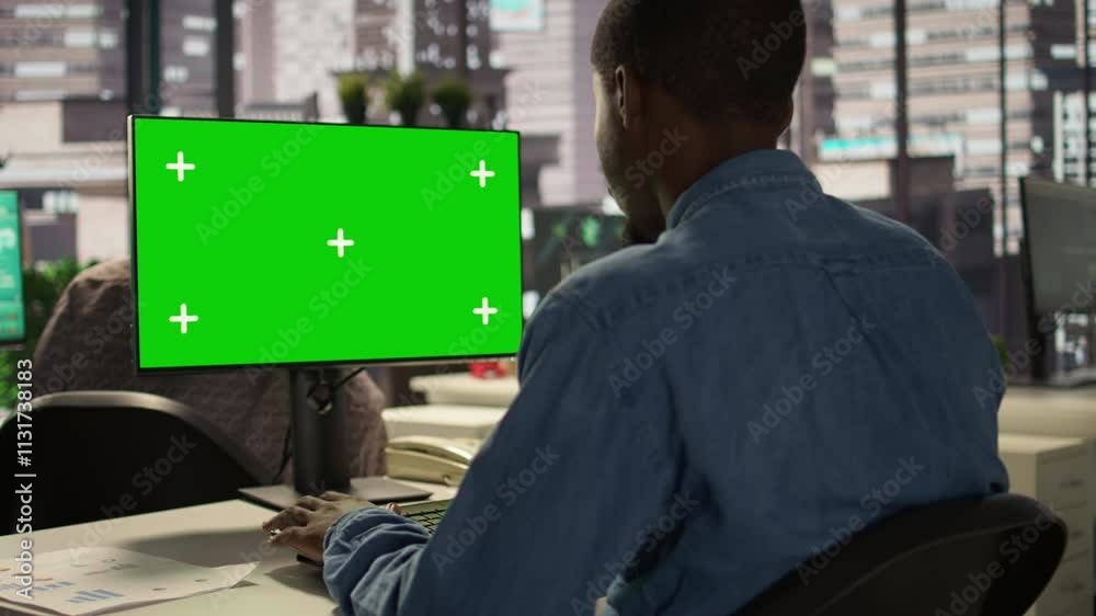 African American businessman at desk with mockup screen analyzing financial data and developing growth strategies to achieve enterprise success. Analyst managing important tasks. Camera B.