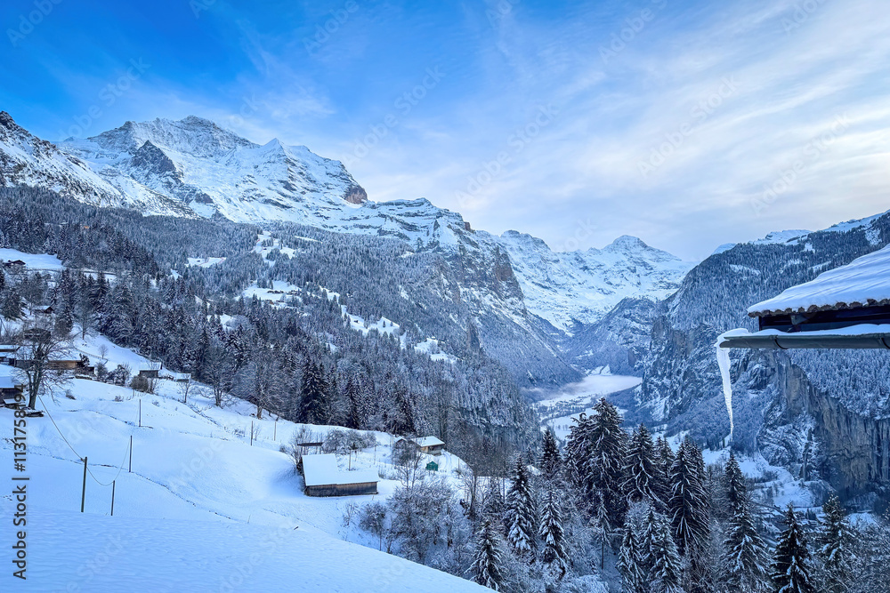 Panoramic view of Lauterbrunnen Valley, Switzerland seen from Wengen with snowcovered Breithorn (right) and Jungfrau (left) mountain in winter against blue sky with clouds