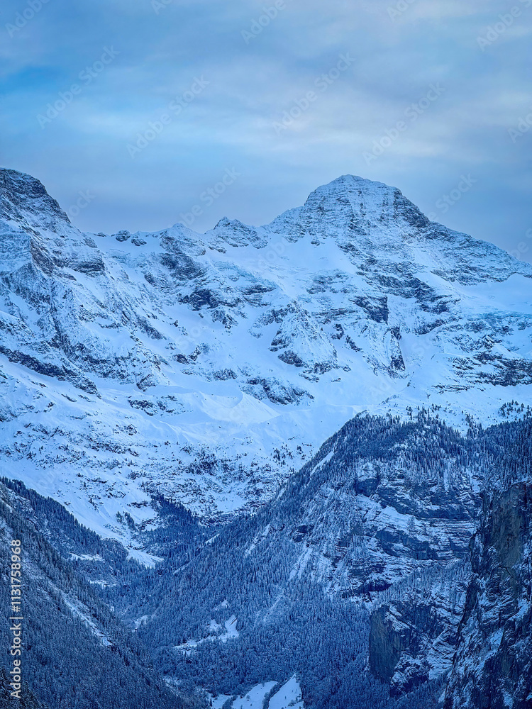 Scenic view of Lauterbrunnen Valley and Breithorn mountain, Switzerland seen from Wengen in winter against blue sky with clouds