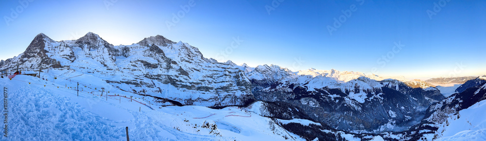 Panoramic view of upper Lauberhorn Ski World Cup race course against snowcapped mountains in Wengen, Switzerland on a beautiful morning with blue sky