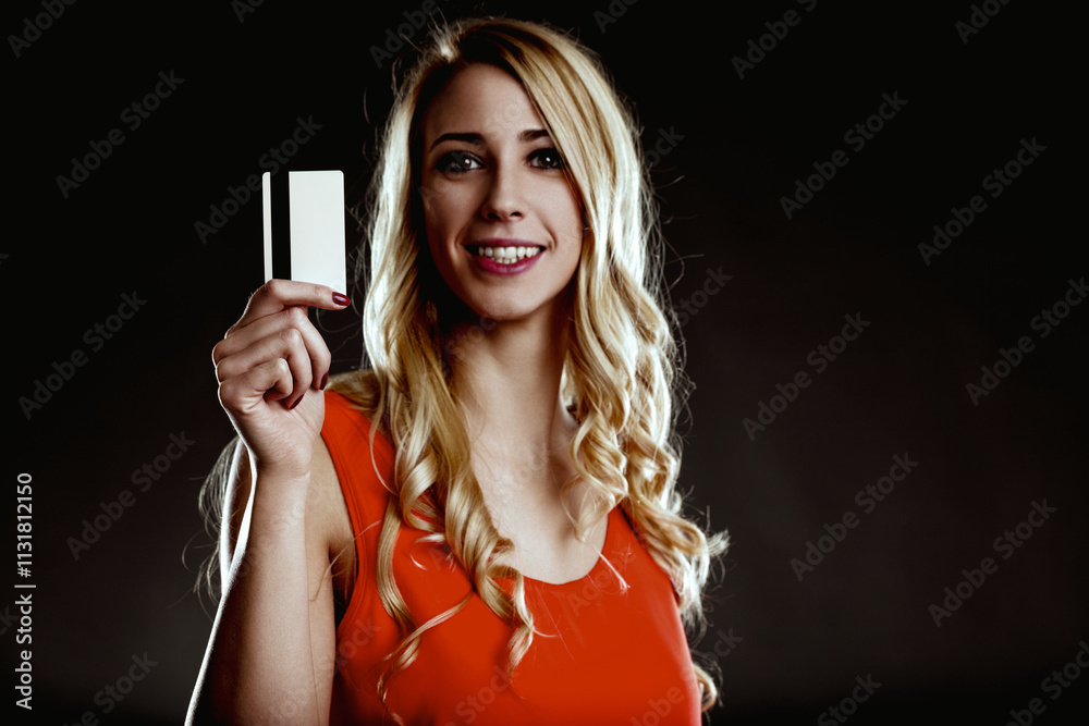 Naklejka premium Smiling woman showing credit card on dark background
