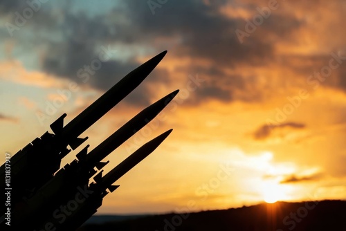 Silhouettes of three missiles point skyward as the sun sets, casting an intense and vivid backdrop, evoking themes of militarization and power. photo