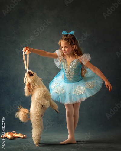 Obraz na płótnie A ballerina girl in a ballet skirt and pointe shoes poses with poodle dog. Little adorable child ballerina in ballet tutu with puppy practicing classic choreography in ballet school, in studio w salonie