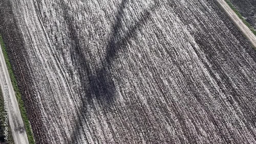 Schattenriss eines drehenden Rotors eines Windrads in einem Acker von oben gesehen