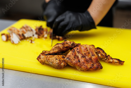 The cook cuts the fried chicken meat on a cutting board. photo