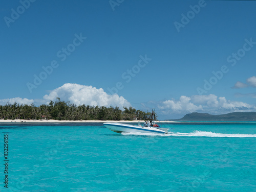 Tableau sur toile Speedboat cruising through the emerald tropical sea, with palm-lined beaches and sandy shores of Managaha Island in Saipan