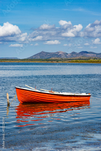 pretty red boat moored in the sea in Sardinia with mountain  in background un...