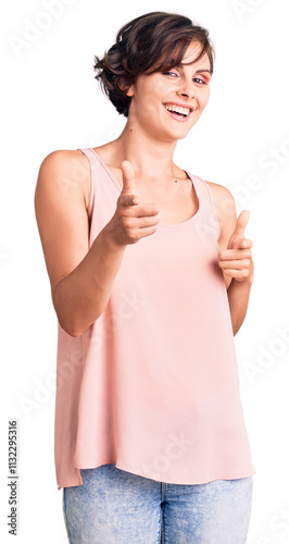 Beautiful young woman with short hair wearing casual style with sleeveless shirt pointing fingers to camera with happy and funny face. good energy and vibes.