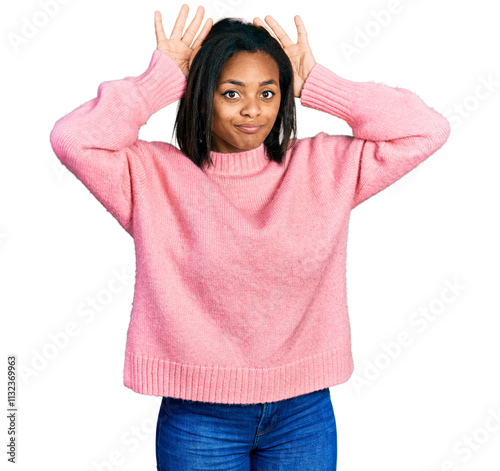 Beautiful hispanic woman wearing casual winter sweater doing bunny ears gesture with hands palms looking cynical and skeptical. easter rabbit concept.