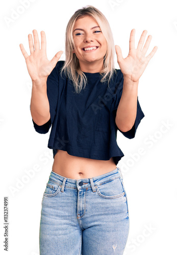 Young beautiful blonde woman wearing casual t-shirt showing and pointing up with fingers number ten while smiling confident and happy.
