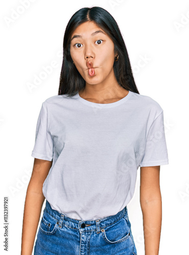 Beautiful young asian woman wearing casual white t shirt making fish face with lips, crazy and comical gesture. funny expression.