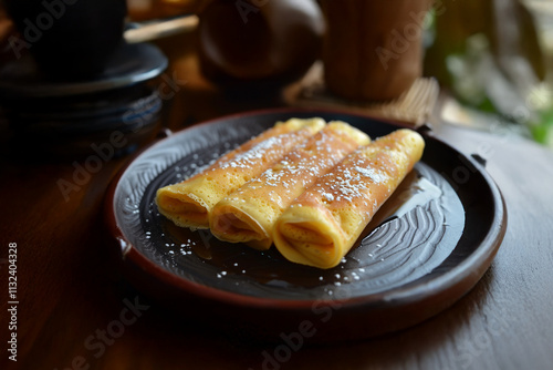 Crêpes traditionnelles roulées saupoudrées de sucre glace, servies sur une assiette en céramique rustique, célébrant la Chandeleur, une fête chrétienne marquée le 2 février. photo