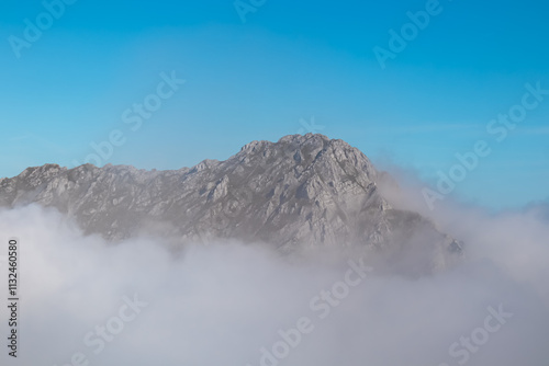 Rugged mountain peak Vrtaca seen from Begunjscica, Loibl Pass, Karawanks, Slovenia Austria. Wanderlust Slovenian Alps in summer. Valley covered with clouds. Peace, tranquility in alpine wilderness photo