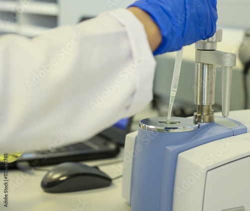 Close-up of a laboratory scientist using a pipette with an advanced FTIR spectrometer for chemical sample analysis. High-tech equipment for precise measurements in research and industrial laboratories photo