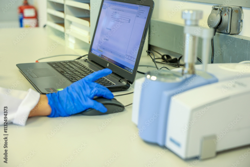 Scientist analyzing data using a laboratory computer and advanced FTIR spectrometer. Professional research environment for chemical analysis, technology, and laboratory science in modern industries