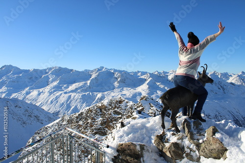 A woman riding a goat on top of the Alps