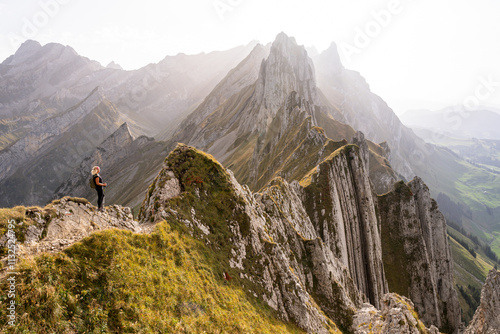 Young woman hiking in Appenzell Innerrhoden canton of Swiss Alps, Switzerland. Rocky mountain peaks on the background photo