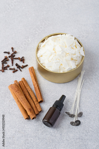 Soy vox in bulk, in a metal container, wicks, aroma oil, cinnamon, spices on a light background. Making handmade candles for Christmas.