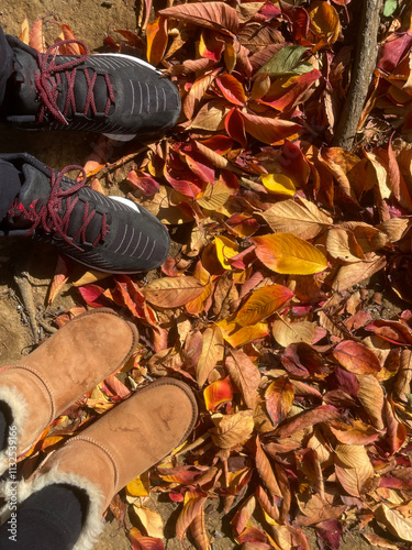 fall leaves on the ground and two pairs of feet in shoes, colorful autumn leaves