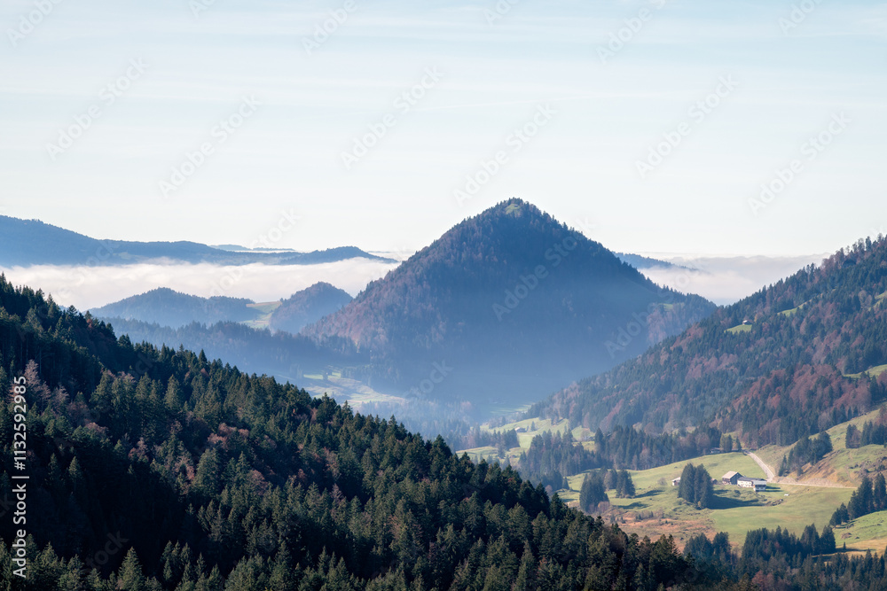 Fototapeta premium Berglandschaft mit Waldhügeln und Nebeldecke im Tal bei klarem Himmel