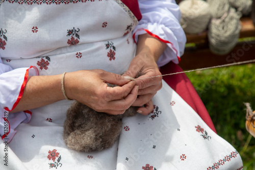 A woman spins woolen thread by hand.