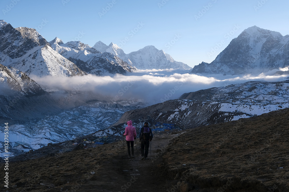 Fototapeta premium Silhouettes of hiking people and amazing panorama with peaks above clouds from Kala Patthar viewpoint. Everest Base Camp, Sagarmatha National Park, Khumbu valley, Nepal, Himalayas