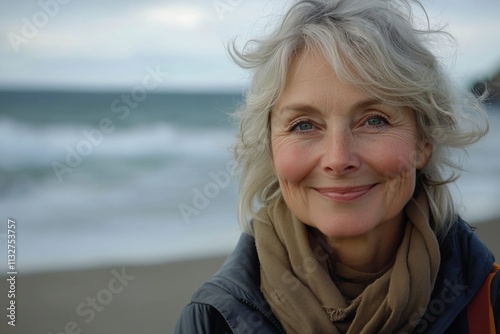 Portrait of a smiling senior woman on the beach with the sea behind her.