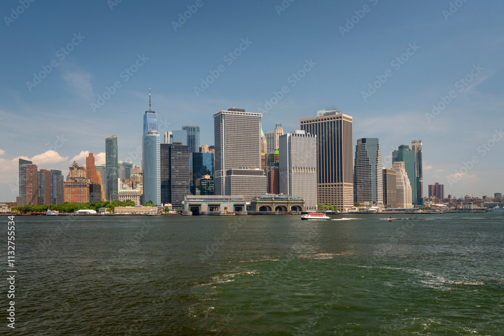 Obraz premium Stunning view of the Lower Manhattan skyline, including One World Trade Center, seen from across the water on a clear day in New York City.