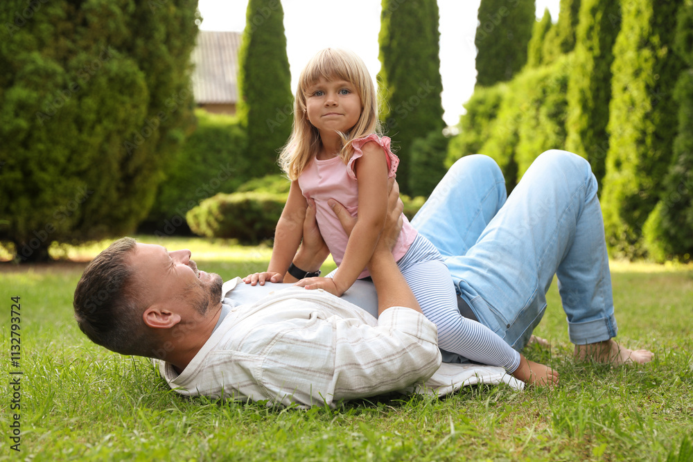 Fototapeta premium Father and his daughter spending time together on green lawn in park