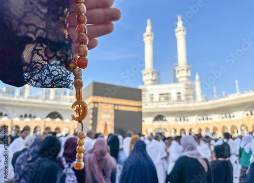 Islamic background with space for text. Muslim Rosary with a crescent moon in female hands of a pilgrim against the background of the Kaaba, the Sacred Mosque and pilgrims performing Hajj.