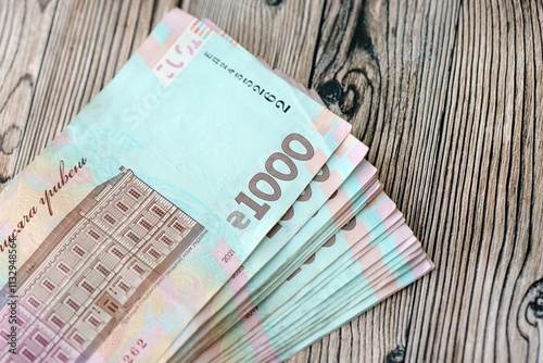 Big amount of ukrainian new one hundred hryvnia money bills with modern design on wooden background. Financial concept, business photo