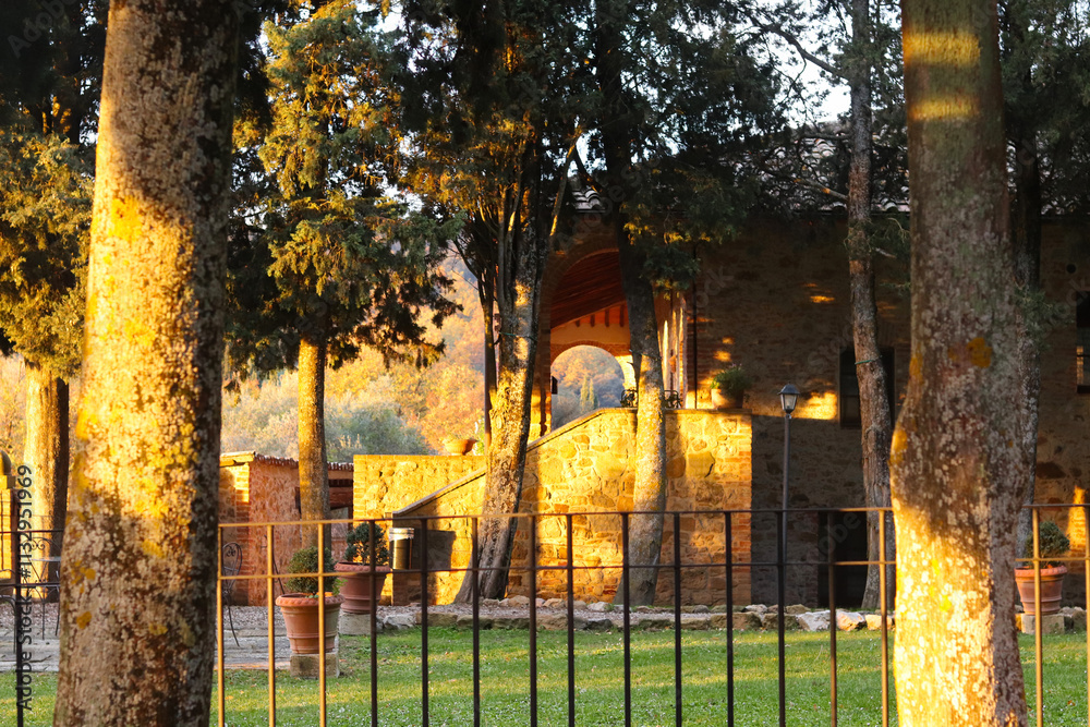 Fototapeta premium Trequanda, Italy - November 25, 2024: The territory of a charming historic building in Tuscany, originally a 13th-century medieval castle, now its a hotel. Features rustic stone walls, arched windows