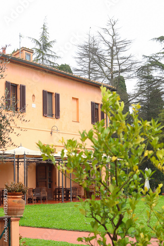 Capannoli, Italy - November 27, 2024: Rustic Tuscan villa surrounded by lush greenery, wooden shutters and a charming outdoor patio. Toscanizzazione hotel in Tuscany. photo