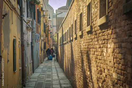 Tourists in a narrow alley looking to the door of their resort, Cannaregio district, Venice, Italy