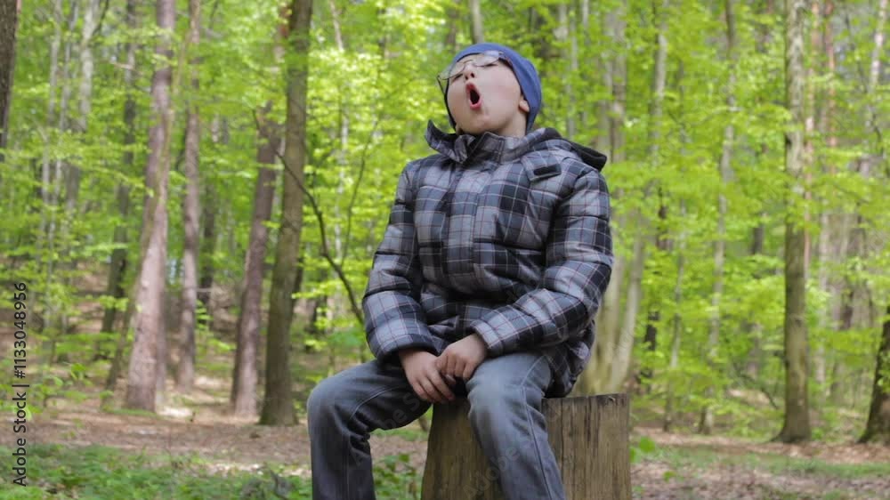 A boy sings in the forest, boy with glasses sitting in the forest and singing a song A boy sings in the forest, boy with glasses sitting in the forest and singing a song
