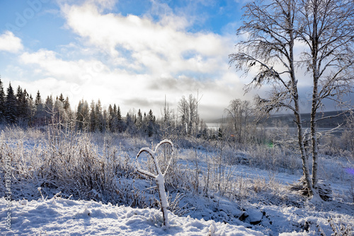 Neuschnee in einer Naturlandschaft in Schweden mit Blick auf See und blauem H...