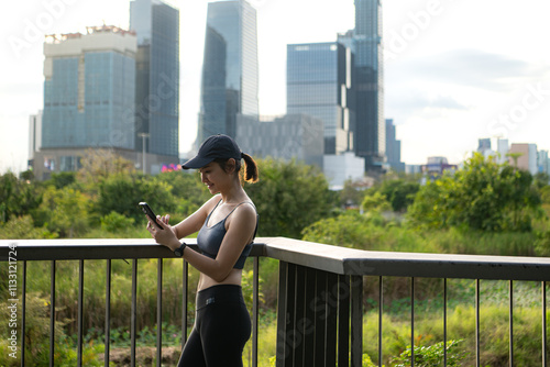 A young woman takes a break during exercise by using smartphone to connect social media and listen to relaxing music photo