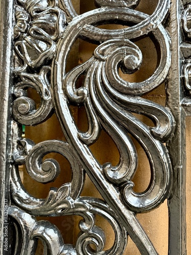 Ornate metalwork with intricate swirling patterns and a polished finish, highlighting craftsmanship and decorative artistry.