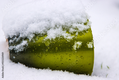 Frosty glossy surface of vibrant green vase covered with snow and water droplets. Flowerpot buried in snow, Winter texture for design and decor concepts. Copy space
 photo