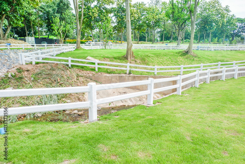 White fence with green grass hill and mountain,blue sky,Lush green golf Course,rest and relax in park near city,big tree in garden,Green grass field,Nature landscape,space for text. photo