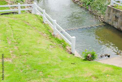 White fence with green grass hill and mountain,blue sky,Lush green golf Course,rest and relax in park near city,big tree in garden,Green grass field,Nature landscape,space for text. photo