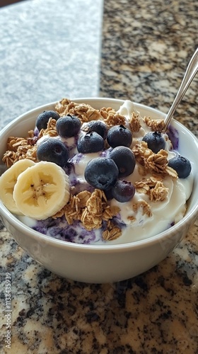 Delicious bowl of yogurt topped with fresh fruit and granola served on a kitc...