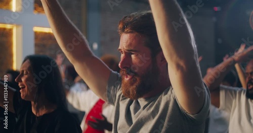 Man raising arms in worship during a spiritual gathering in a church, expressing deep faith, devotion, and emotion alongside a diverse congregation